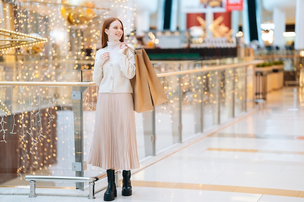 Portrait de toute la longueur d'un modèle féminin à la mode attrayant tenant des sacs à provisions sur l'épaule