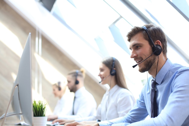 Portrait de travailleur du centre d'appels accompagné de son équipe. Opérateur de support client souriant au travail.