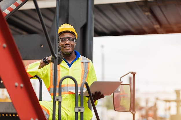 Portrait Travailleur du personnel africain noir sourire heureux travaillant dans le port logistique d'expédition de grues de fret.