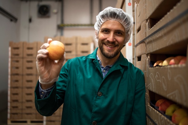 Portrait de travailleur tenant des pommes dans l'entrepôt de l'usine d'aliments biologiques.