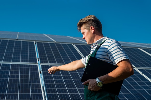 Portrait de travailleur en uniforme de protection debout devant des panneaux solaires