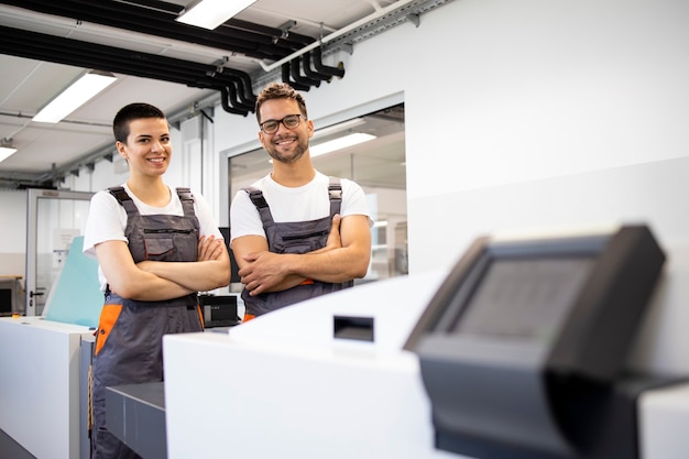 Portrait de travailleurs de l'imprimerie debout devant l'ordinateur pour plaquer la machine dans l'imprimerie.