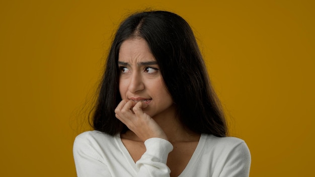 Portrait triste peur inquiète femme ethnique indienne fille en studio fond jaune stressé nerveux