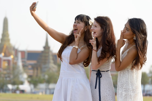 Portrait de trois belles jeunes femmes multiethniques comme amis ensemble dans le parc en plein air