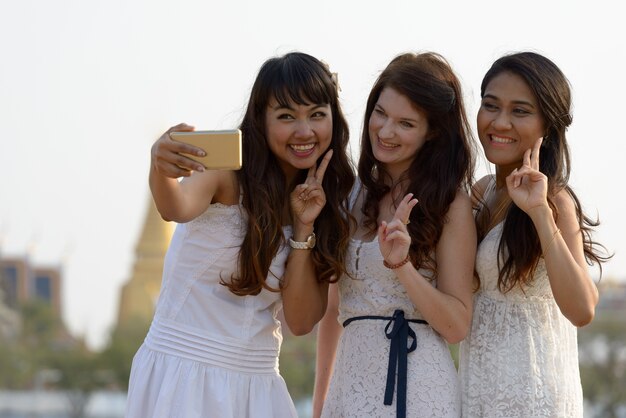 Photo portrait de trois belles jeunes femmes multiethniques comme amis ensemble dans le parc en plein air