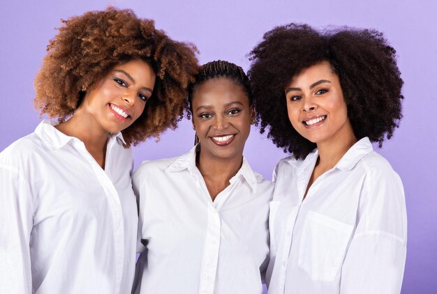 Photo portrait de trois dames africaines s'embrassant montrant l'unité sur fond violet