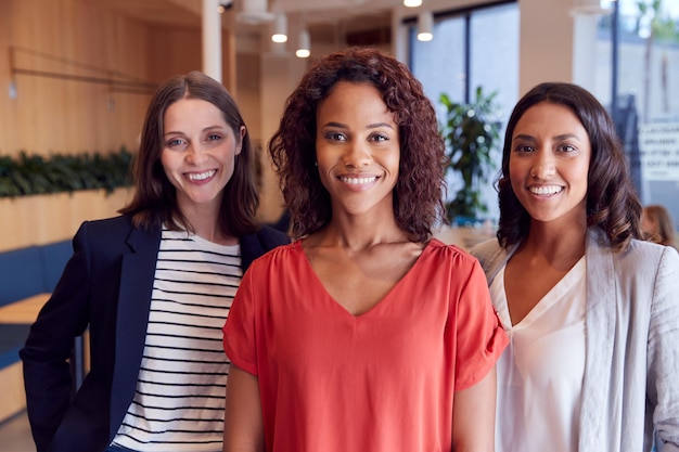 Portrait de trois femmes d'affaires debout dans un bureau ouvert moderne ensemble