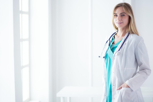 Portrait de trois femmes médecins confiantes debout avec les bras croisés au cabinet médical