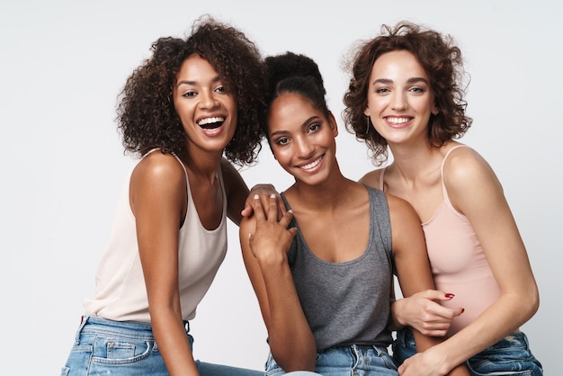 Portrait de trois magnifiques femmes multiraciales debout ensemble et souriant à la caméra
