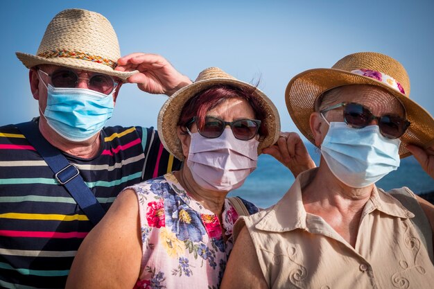 Portrait de trois personnes âgées en vacances à la mer portant un masque médical