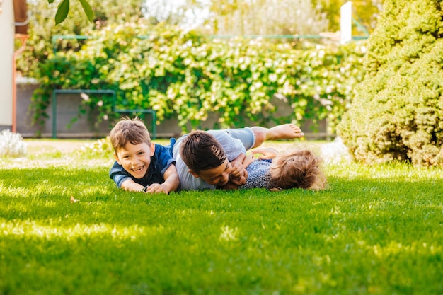 Portrait de trois petits enfants allongés sur une herbe verte