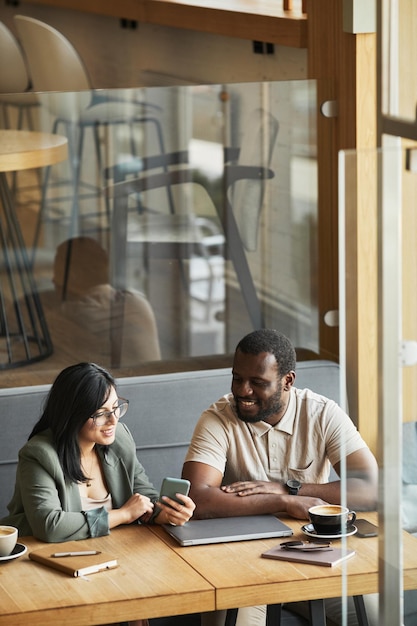 Portrait vertical de deux hommes d'affaires souriants se réunissant à la table du café et discutant du travail, espace de copie