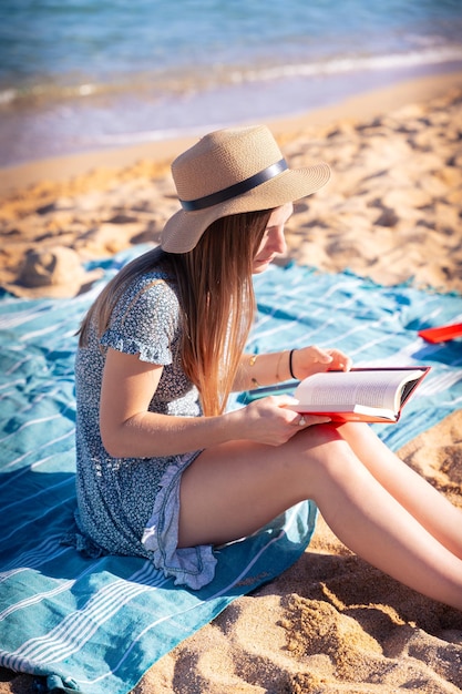 Portrait vertical d'une femme caucasienne avec un livre à la main lisant sur la plage