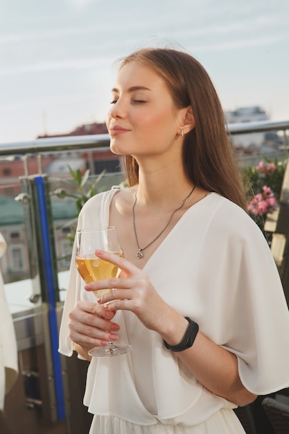 Portrait vertical d'une femme souriante les yeux fermés, appréciant le vin