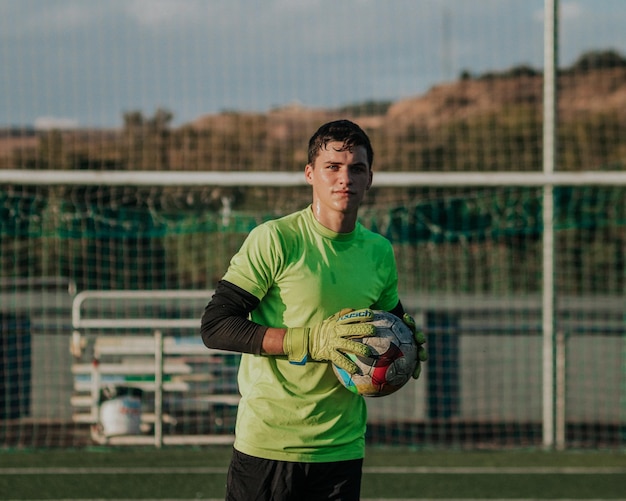 Portrait vertical d'un gardien de but tenant un ballon de soccer.