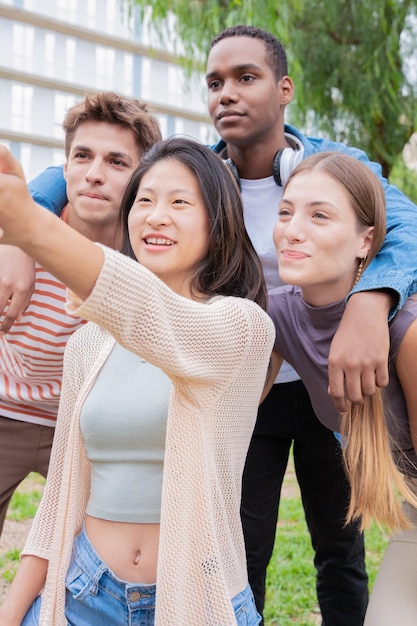 Photo portrait vertical d'un groupe multiracial d'amis étudiants qui rient en prenant un selfie