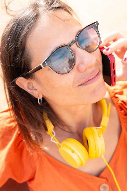 Photo portrait vertical jeune belle fille souriante parlant sur smartphone à l'extérieur