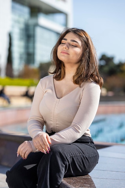 Portrait vertical de jeune fille assise sous le soleil et fermant les yeux Photo de haute qualité