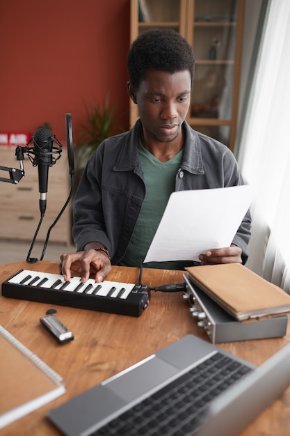 Portrait vertical de jeune musicien afro-américain composant de la musique en studio d'enregistrement à domicile