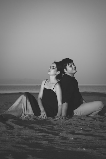 Portrait vertical noir et blanc d'un jeune couple d'amoureux sur la plage à l'éclairage du coucher du soleil