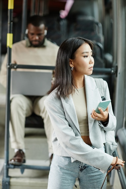 Portrait vertical à la taille d'une femme asiatique élégante regardant la fenêtre d'un bus lors d'un voyage en public...