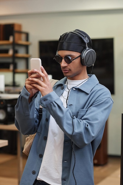 Portrait vertical à la taille d'un jeune homme noir choisissant un smartphone dans un magasin de technologie