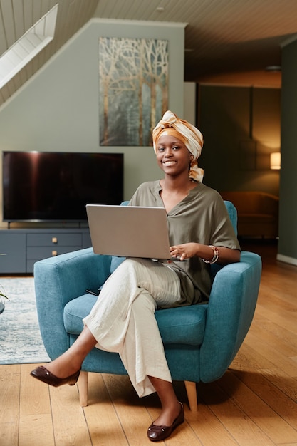 Portrait vertical de toute la longueur d'une jeune femme d'affaires afro-américaine travaillant à la maison et souriant à ...