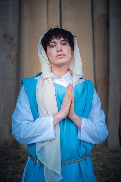 Portrait vertical d'une vierge marie androgyne priant face à la caméra