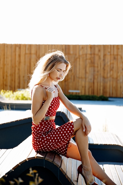 Portrait de vie d'une jeune femme à l'extérieur dans la ville, vêtue d'une tenue rouge: jupe et haut.