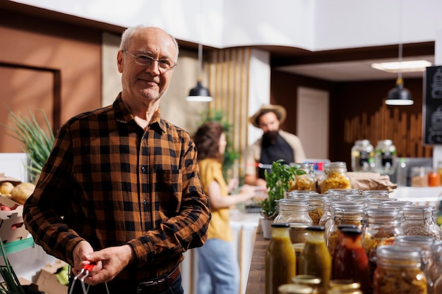 Photo portrait d'un vieil homme à la recherche de légumes cultivés localement dans un magasin écologique zéro déchet. client sénescent faisant des courses, achetant des aliments naturels biologiques dans un magasin de quartier