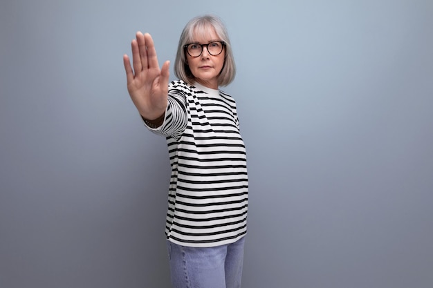 Portrait d'une vieille femme aux cheveux gris dans une image à la mode sur un fond de studio lumineux