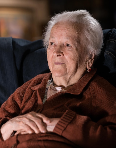 Portrait d'une vieille femme souriante aux cheveux gris posant à la maison