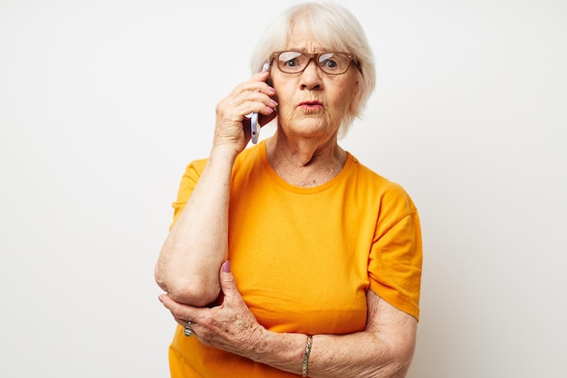 Portrait d'une vieille femme sympathique dans un t-shirt jaune posant la communication par téléphone vue recadrée