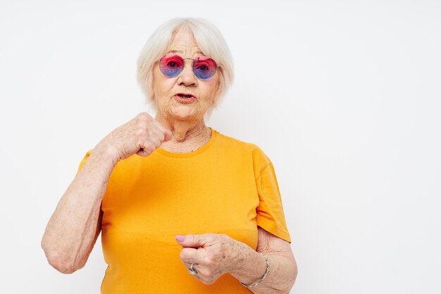 Portrait d'une vieille femme sympathique dans un t-shirt jaune posant fond isolé