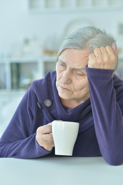 Portrait d'une vieille femme triste buvant du thé