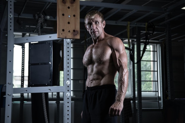 Portrait d'un vieux bodybuilder brutal avec un visage sérieux posant dans la salle de gym Homme adulte musclé avec torse nu
