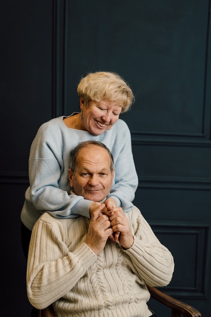 Portrait de vieux couple femme et mari étreignant et souriant. Fond bleu foncé. Heureux amoureux à la retraite. Arrêtez l'âgisme. . Photo de haute qualité