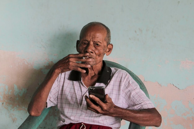 Un portrait d'un vieux grand-père indonésien appelant un smartphone