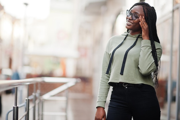 Portrait de la ville d'une jeune femme positive à la peau foncée portant un sweat à capuche vert et des lunettes