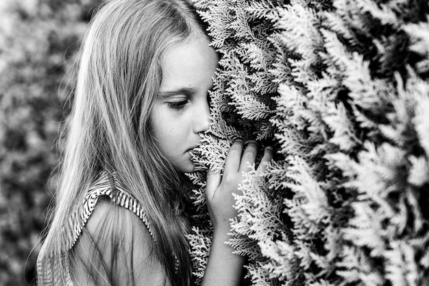 Portrait visage de candide offensé bouleversé petite fille de huit ans avec de longs cheveux blonds sur fond de plantes pendant les vacances d'été voyage gen z concept de santé mentale tonique en blanc noir