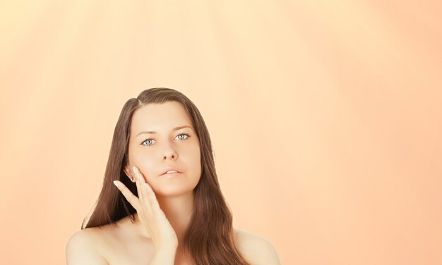 Portrait de visage ensoleillé de la peau bronzée de la jeune femme et cosmétiques de beauté beau modèle féminin brune avec bronzage naturel à l'aide d'un produit de protection solaire