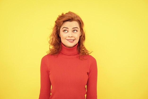 Portrait de visage de femme rousse assez rêveuse se mordre la lèvre sur les émotions de fond jaune