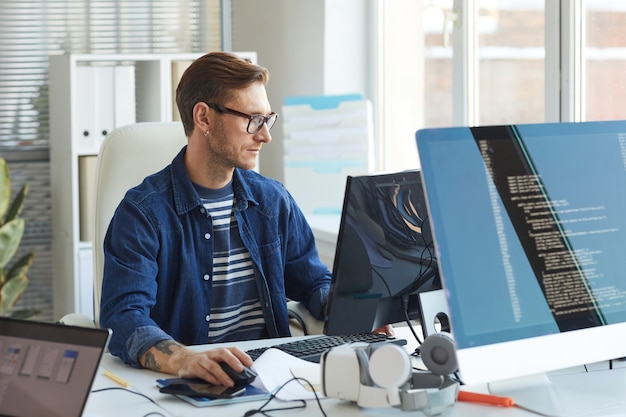 Photo portrait de vue latérale d'un développeur informatique moderne utilisant un ordinateur au bureau tout en travaillant sur des jeux et des logiciels vr, espace de copie