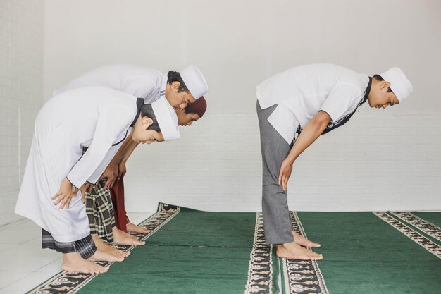 Portrait de vue latérale d'un groupe de musulmans priant en congrégation avec un mouvement d'inclinaison dans la mosquée