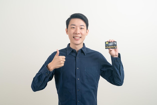 Portrait young Asian man holding credit card sur fond blanc