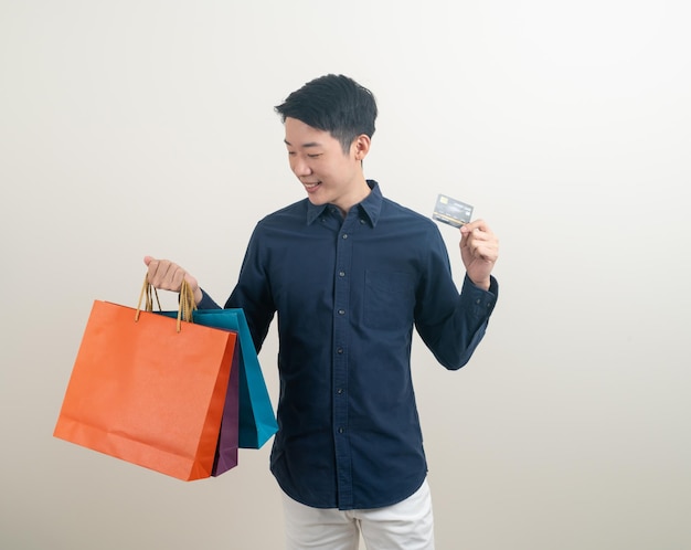 Portrait young Asian man holding credit card et panier sur fond blanc