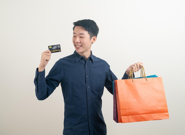 Portrait young Asian man holding credit card et panier sur fond blanc