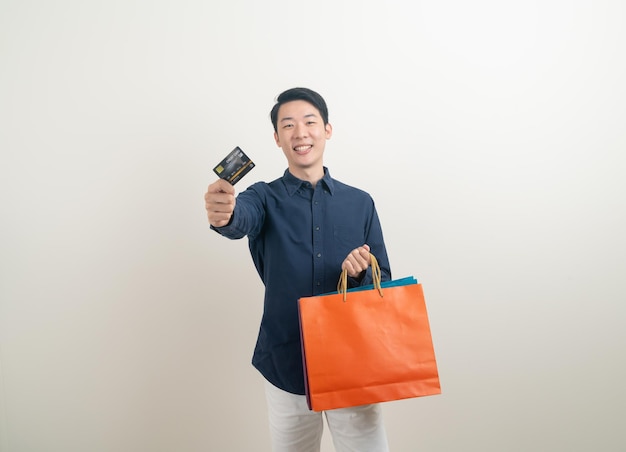 Portrait young Asian man holding credit card et panier sur fond blanc