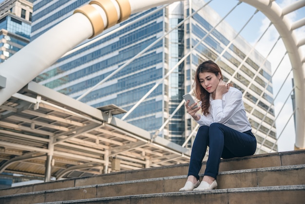 Les portraits de la belle femme asiatique ont l&#39;air de la confiance tient le téléphone portable.