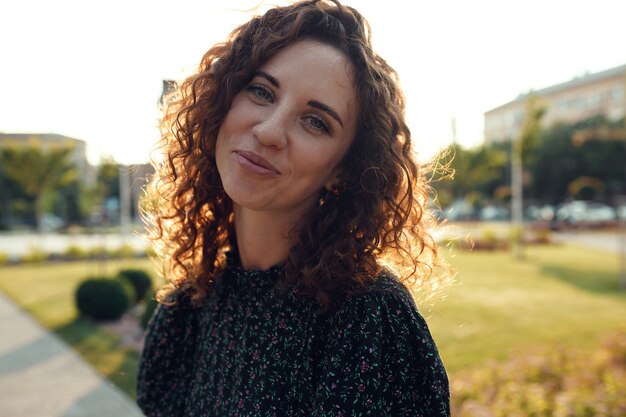 Portraits d'une charmante fille rousse avec des taches de rousseur et un joli visage. La jeune fille pose pour la caméra dans le centre-ville. Elle a une bonne humeur et un doux sourire